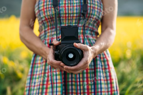 Preview: Woman staying in field with camera