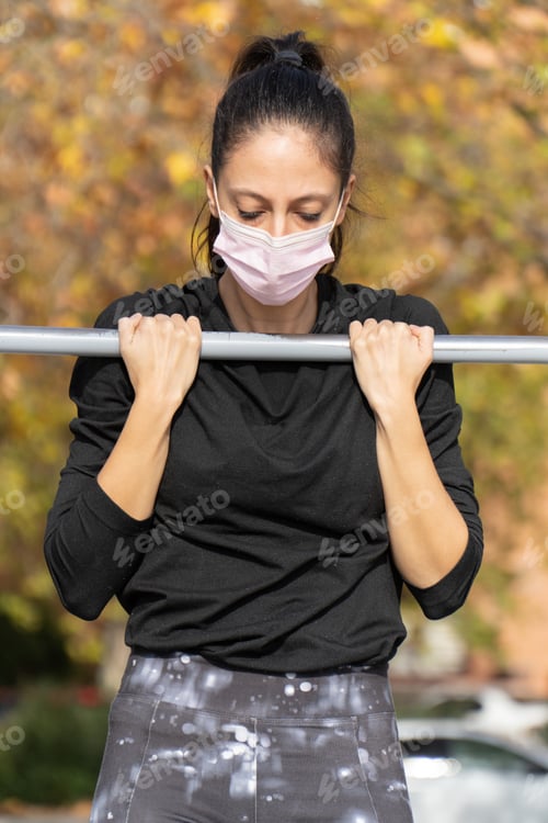 Preview: Vertical shot of a young lady exercising wearing a sanitary mask - concept of the new normal