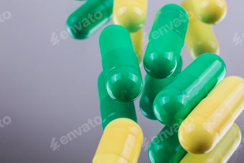 Preview: yellow and green capsules medications on a mirrored background