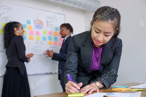 Preview: Businessman and businesswomen, in office, brainstorming, sticking notes to whiteboard