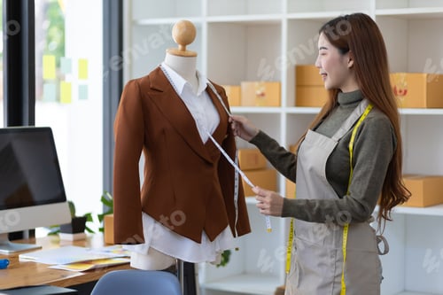 Preview: Fashion designer working in workshop measuring shirt sample on dummy.