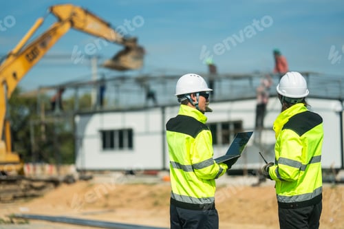 Preview: An engineer in visibility jacket and helmet working on construction site.