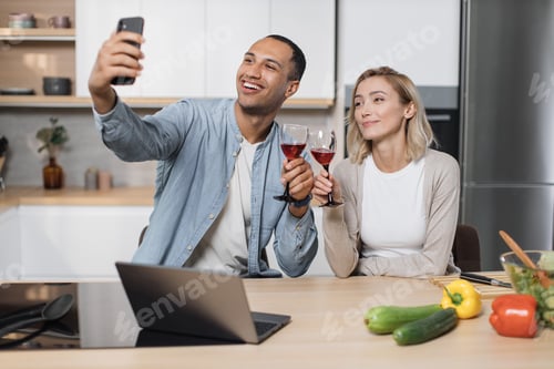 Preview: Cute multinational couple taking selfie or having video conversation with friends