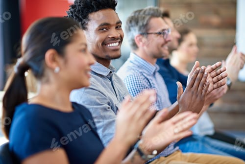 Preview: Confident businessman smiling at the camera while applauding along with coworkers
