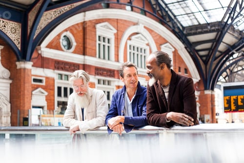 Preview: Three mature men at train station, standing together, talking