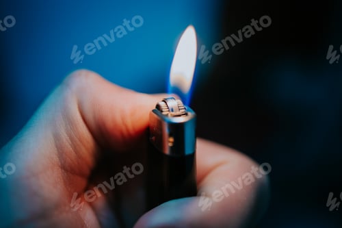 Preview: Male hand holding a flaming lighter with a black background