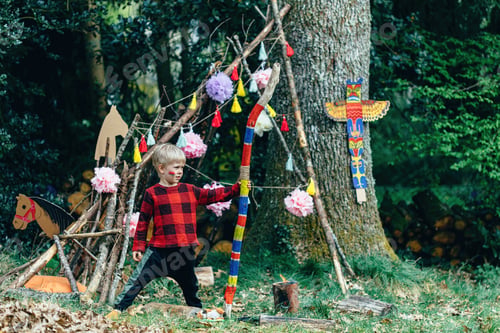 Preview: a child playing Indians near a hut made of branches