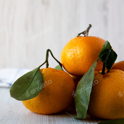 Preview: Fresh ripe unpeeled tangerines over white wooden surface, side view. Close-up.