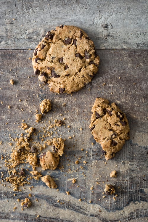 Preview: Chocolate chip cookies crumbling on rustic wooden table