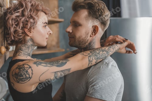 Preview: tattooed couple hugging and looking at each other