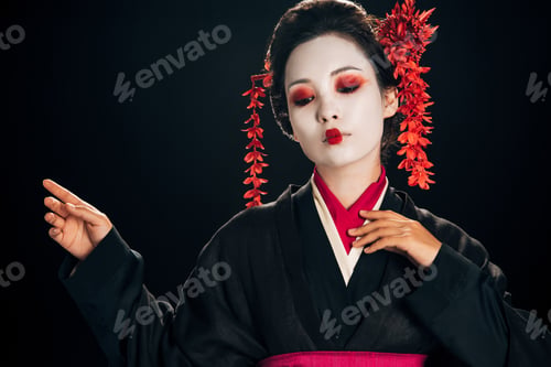 Preview: beautiful geisha in black and red kimono and flowers in hair gesturing isolated on black with copy