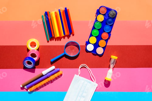 School supplies and protective mask during classes on a colorful and cheerful background.