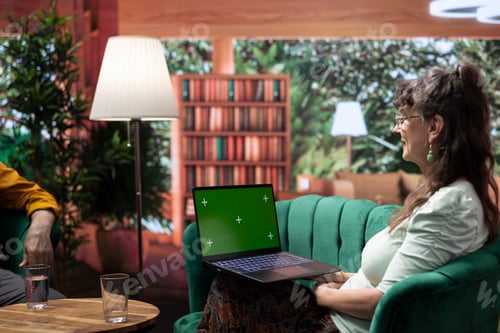 Preview: Mature people enjoying leisure time at home with green screen on laptop