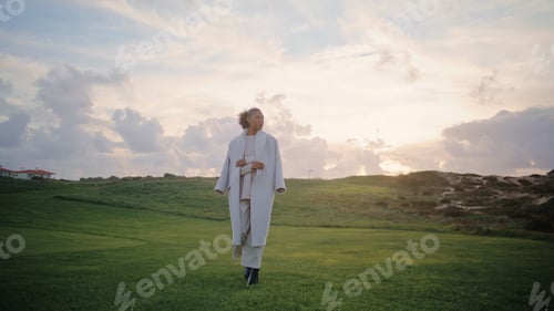 Preview: Gorgeous woman walking field in stylish coat. Thoughtful african american dream