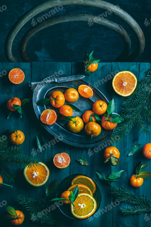 Preview: Tangerines with green leaves on a green wooden table in a rustic style surrounded by spruce branches