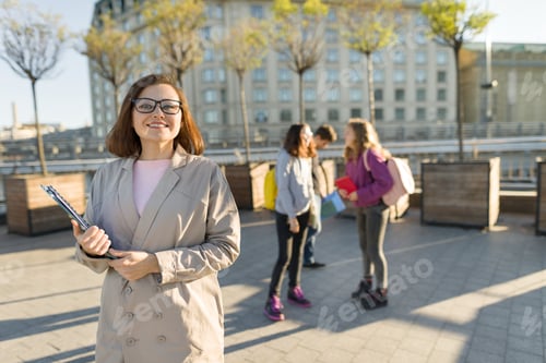 Visualização: Retrato de professora madura sorridente em óculos com prancheta