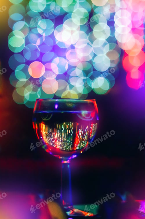 Preview: Beautiful glass with wine, champagne on a background with multicolored Christmas bokeh.