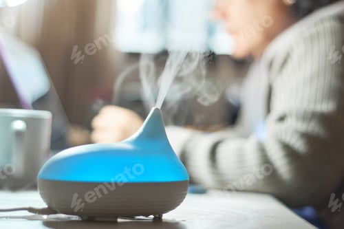 Preview: Woman uses aroma diffuser while working. Aromatherapy concept.