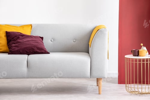 Preview: Purple and orange cushion on grey sofa next to table in grey and