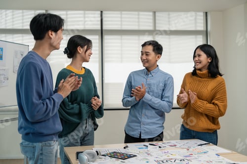 Preview: Asia team creative in smart casual wear discussing phone application design celebrate giving five
