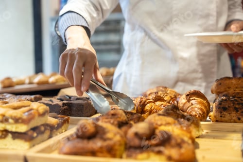 Preview: Baker serving fresh pastry with tongs at cafe