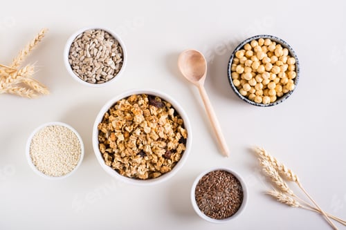 Preview: Baked granola in a bowl and different seeds in bowls on the table. Healthy breakfast. Top view