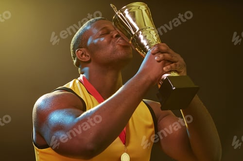 Preview: Muscular Black Man Kissing Trophy in Sports Competition