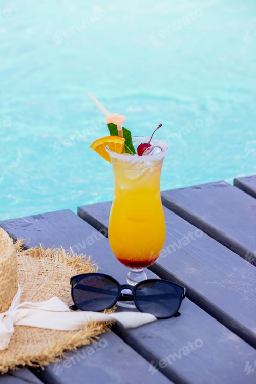 Preview: A nice cocktail, hat and sunglasses by the pool