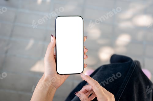 Preview: A woman sits outdoors and uses her smartphone. the smartphone with a white screen mockup.