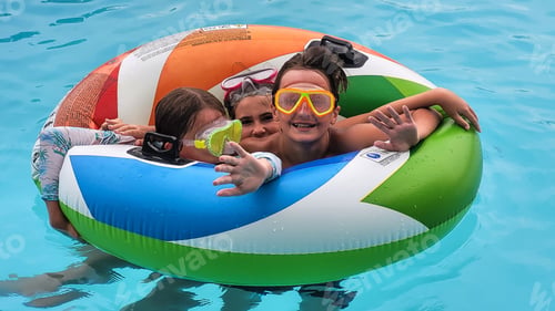 Preview: Generation z siblings in a pool on a round float having fun together on vacation.