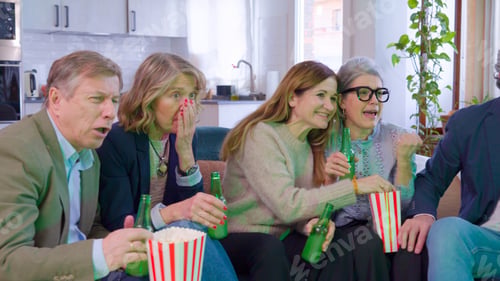 Preview: Group of senior friends watching TV with excitement at home