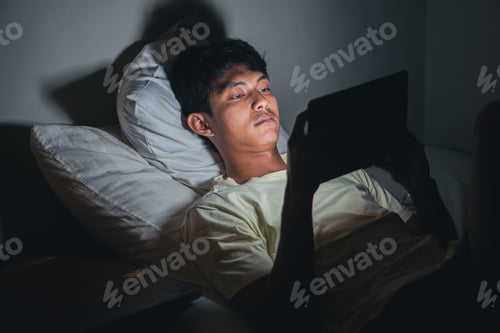 Preview: Man using tablet in bed at night