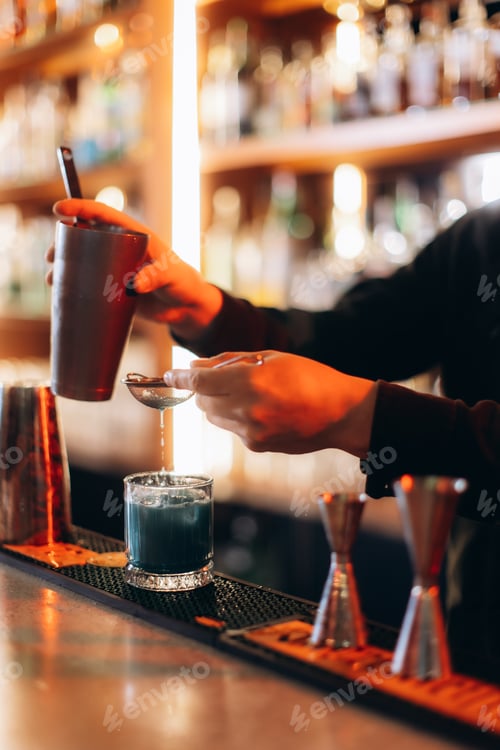 Preview: Professional Bartender Mixing a Vibrant Cocktail in a Modern Bar Setting