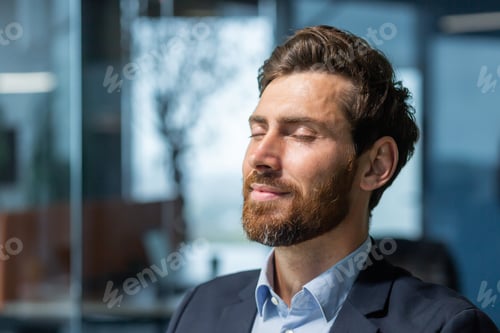 Preview: A young man who closed his eyes and rests at the workplace. Sitting relaxed in the office