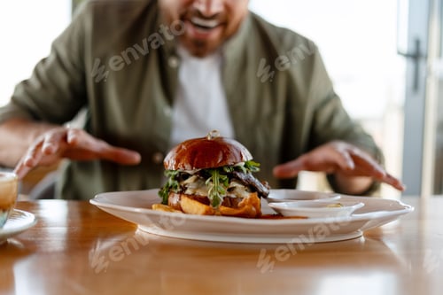 Preview: Hungry man reaching for gourmet burger with fries and dipping sauce