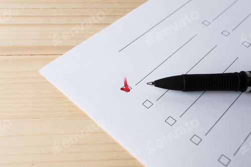 Preview: Checklist with a pen and a red mark on a white sheet of paper on a wooden table
