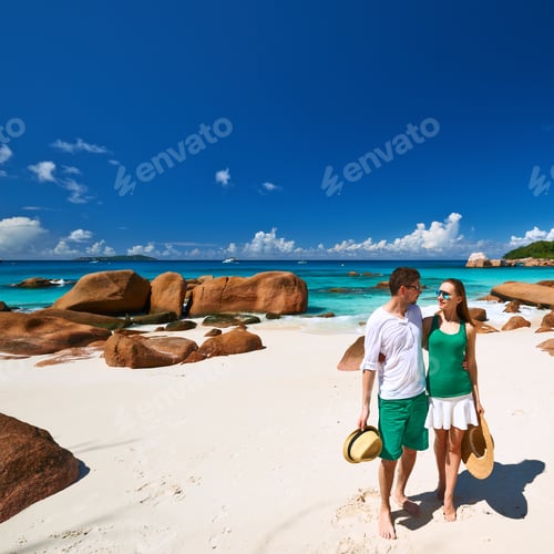 Preview: Couple In Green Walking On A Tropical Beach At Seychelles