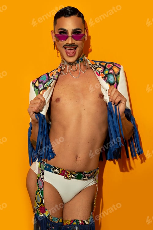 Preview: Portrait of a happy young drag queen smiling in a colorful dress on a yellow background.