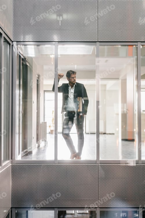 Preview: Businessman standing at window, thinking