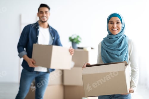Preview: Happy muslim family holding moving supplies in their new apartment