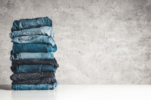 Preview: Stack of blue jeans on a gray background