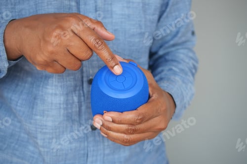 Preview: Person adjusts blue wireless speaker in casual setting