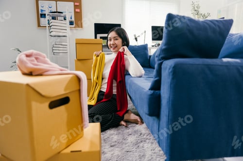 Preview: Young entrepreneur preparing clothes for shipping in her home office