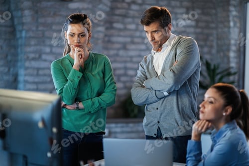 Preview: Group of pensive entrepreneurs analyzing something on computer screen in the office.