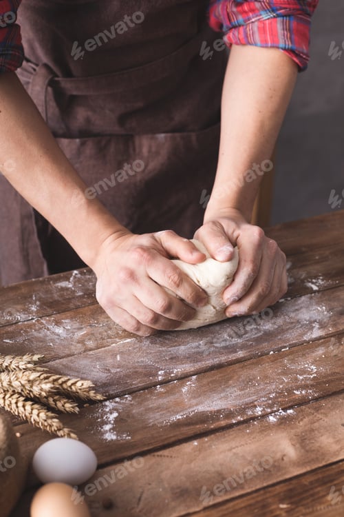 Preview: Baker male hand kneading or making dough and bakery ingredients for homemade bread cooking on table