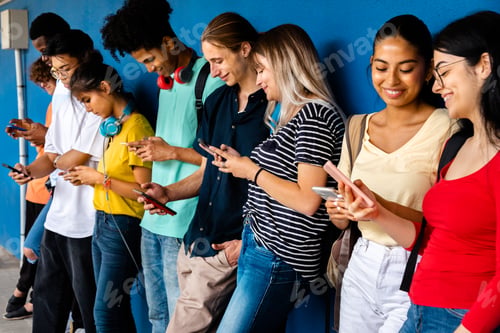 Preview: Happy multiracial high school students using cellphone standing against blue wall. Social media.