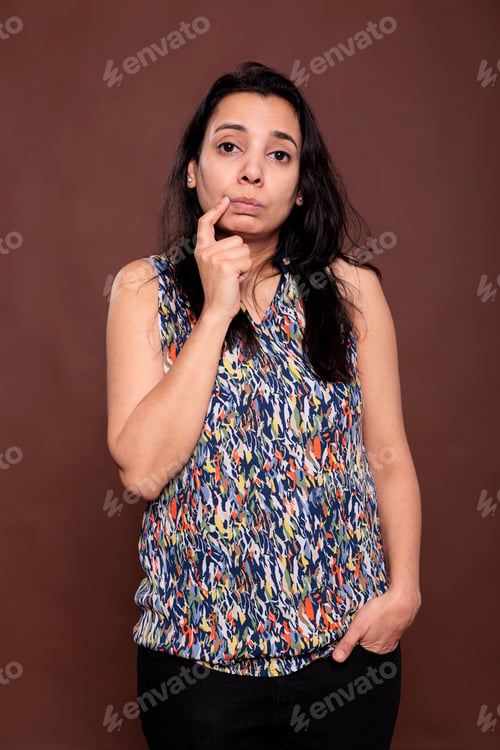 Preview: Cute thoughtful indian woman holding finger on cheek