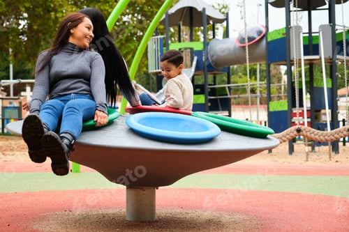 Preview: Lesbian couple laughing while playing with their son in the playground.