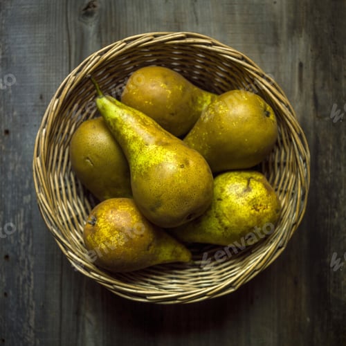 Preview: Overhead shot of fresh pears in a straw basket on a wooden table