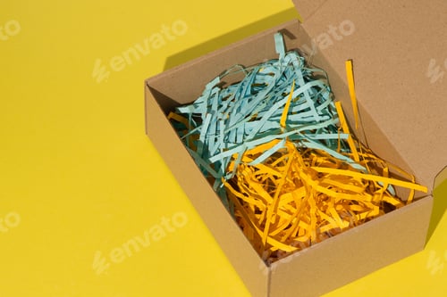 Preview: Gift wrap. Box with yellow and blue paper filling. View from above.